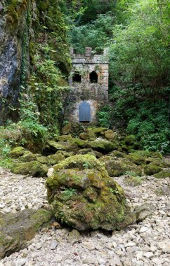 Slovenya 'nın Sneznik şatosunun yanındaki küçük bir göletin kurumuş yatağında yosun kaplı büyük bir taş ve ortaçağ binası.