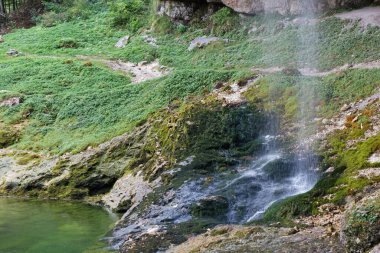 İtalya, Chiusaforte yakınlarındaki Goriuda şelalelerinden birinin ayrıntıları, yaz ortasında mağarası ve göleti arasında.
