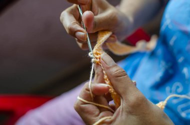 Evdeki iplik yumağından örgü ören bir kadının yakın çekim görüntüsü.