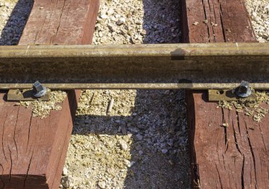 Sürgülü demiryolu ve ahşap uykucular zeminde ezilmiş taşların üzerinde yatıyordu. Uyuyanların kırmızı renkleri var çünkü demir oksitle döllenmişler.