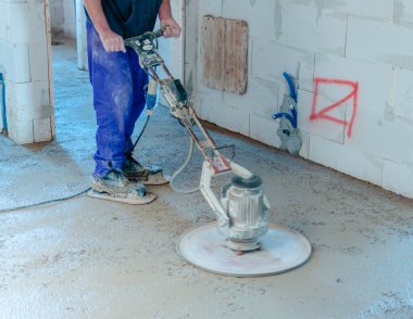 Seviyelendirme için dönen diski olan bir makine tarafından öğütülmüş yarı kuru zemine vurup öğütülmüş. hareket bulanık diski