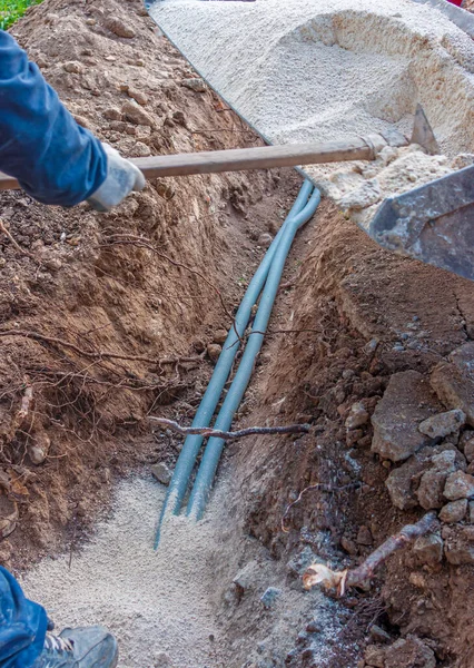 工人们用挖在地下的壕沟里的细沙盖住了电线 图库图片