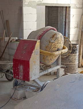 concrete mixer installed on the construction site next to a pile of sand and gravel. clipart