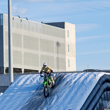 Bari, Italy - April 24, 2023: motocross rider performing jumps tricks dirt bikes, rider wears colorful protective gear helmets. Bikes midair showing off dynamic stunts during the 