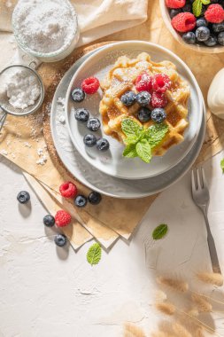 Geleneksel Belçika waffleları, mutfak tezgahına taze ahududu ve yabanmersini serpiştirilmiş pudra şekeri serpiştirilmiş..