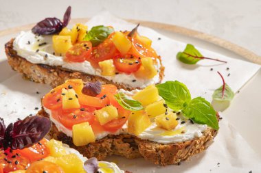 Kızarmış domatesli İtalyan bruschetaları, krem peynir, ananas dilimleri ve mutfak tezgahında otlar. Hizmet etmeye hazır