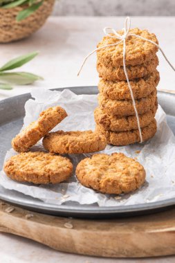 Stack of homemade oatmeal cookies, healthy breakfast cereal oat crackers and mug of milk with coffee on white kitchen countertop. Top view. Flat lay