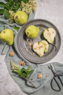 Fındık ile lezzetli armut. Çiçeklerle süslenmiş bir masa ve plakaya kesilmiş bir tabak armut