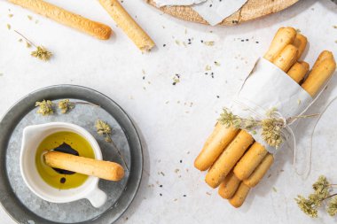 Breadsticks grissini. Bread sticks with sesame seeds, oregano and olive oil and balsamic vinegar on kitchen countertop. Top view. Flat lay with copy space