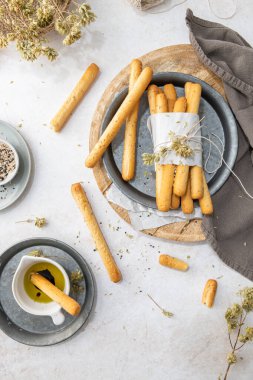 Breadsticks grissini. Bread sticks with sesame seeds, oregano and olive oil and balsamic vinegar on kitchen countertop.