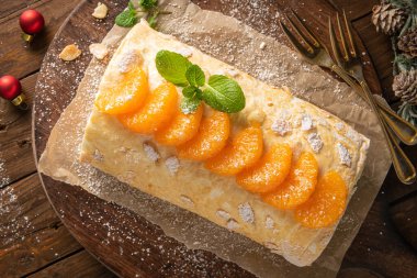 Meringue roll cake with cream, tangerine. Roulade, christmas dessert served in ceramic plate. Pavlova sweet dessert.