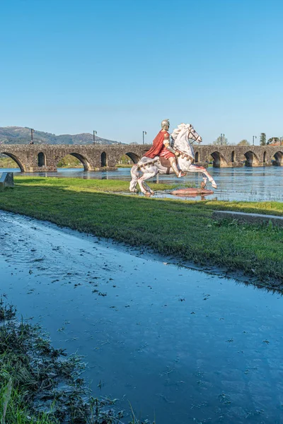 Statue of Roman soldier in front of the Roman bridge crossing the Rio Lima in Portugal.