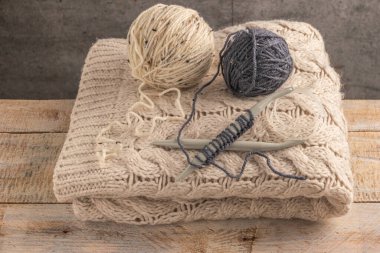 Örgü projesi devam ediyor. İplik yumağı ve örgü iğneleriyle örülmüş bir örgü parçası..