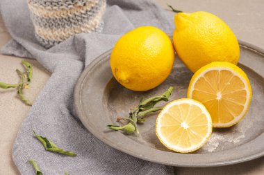 Lemon and sliced lemon in a dish and a grey napkin green leaf , blank space for advertising