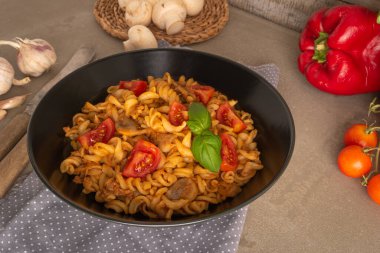 Fusilli pasta with tuna in tomato sauce in a skillet on a dark grey slate, stone or concrete background. Top view with copy space.