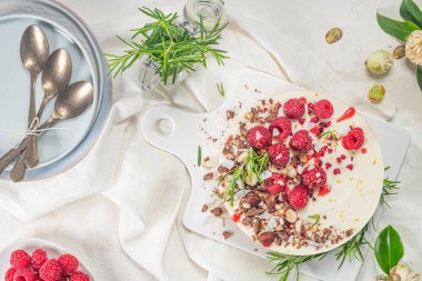Mutfakta ahududu, çikolata, fındık ve biberiye yapraklı cheesecake.