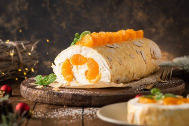 Meringue roll cake with cream, tangerine. Roulade, christmas dessert served in ceramic plate. Pavlova sweet dessert.