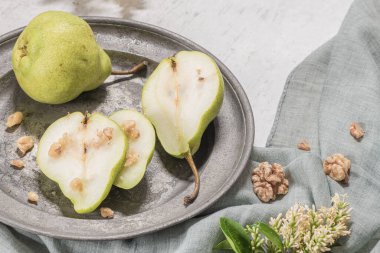 Fındık ile lezzetli armut. Çiçeklerle süslenmiş bir masa ve plakaya kesilmiş bir tabak armut