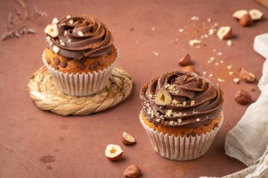 Çikolata parçalı kekler çikolata ganache ve fındıkla süslenmiş mutfak tezgahında..