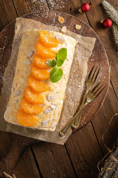 Meringue roll cake with cream, tangerine. Roulade, christmas dessert served in ceramic plate. Pavlova sweet dessert.