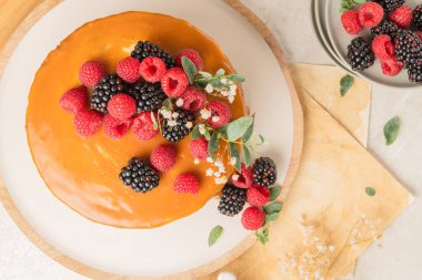 Üzeri mascarpone kremalı ve tuzlu karamel kaplı lezzetli çikolatalı pasta. Kırmızı meyvelerle süslenmiş. Hafif arkaplan