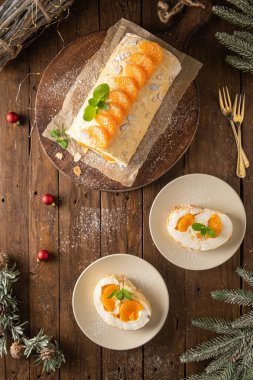 Meringue roll cake with cream, tangerine. Roulade, christmas dessert served in ceramic plate. Pavlova sweet dessert.