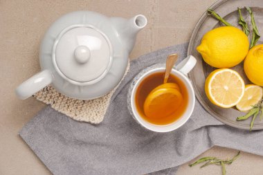 Cup of tea and lemon. A cup of tea with lemon, mint, ginger and honey on on grey table. Flat lay. Top view