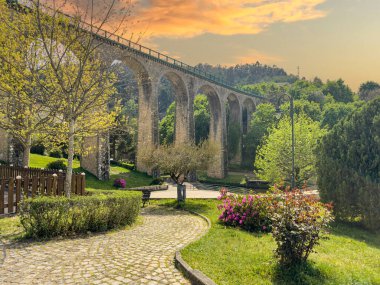 Vouzela, Viseu, Portekiz 'deki eski demiryolu köprüsü ve bahçesi güneşli bir öğleden sonra.