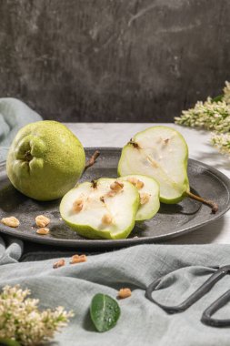 Fındık ile lezzetli armut. Çiçeklerle süslenmiş bir masa ve plakaya kesilmiş bir tabak armut
