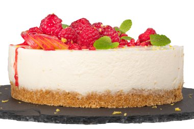 Beyaz zemin üzerinde ahududu, erik ve nane yapraklı cheesecake.