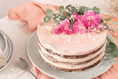 Taze güllerle çikolatalı, çıplak pasta ve beyaz arka planda İsviçre tereyağı.