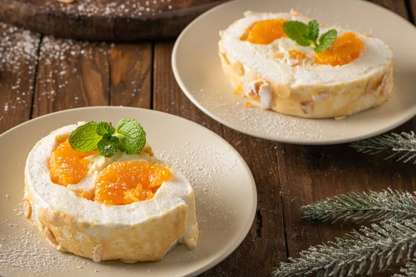 stock image Meringue roll cake with cream, tangerine. Roulade, christmas dessert served in ceramic plate. Pavlova sweet dessert.