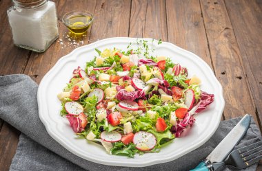 Tahta arka planda yeşil turp peyniri ve domatesli taze salata. İtalyan Akdeniz veya Yunan mutfağı. Vejetaryen yemeği..