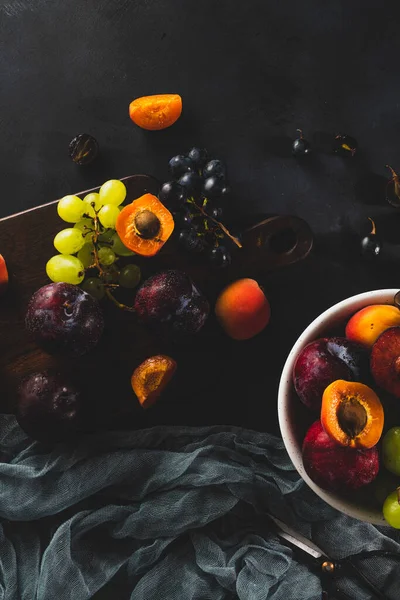 stock image Freshly washed fruits with water droplets. bright high key look conveys freshness. Variety of fresh grapes, apricot and plumes on dark background. Fruit sources of vitamins