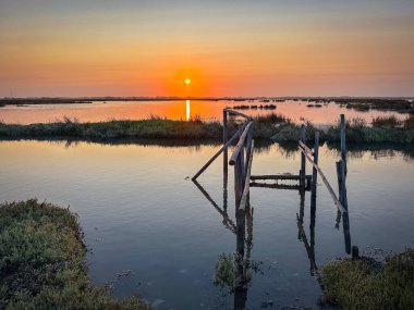 Portekiz 'deki Ria de Aveiro' daki eski ahşap iskelede, gün batımında sakin bir su. Murtosa, Portekiz.