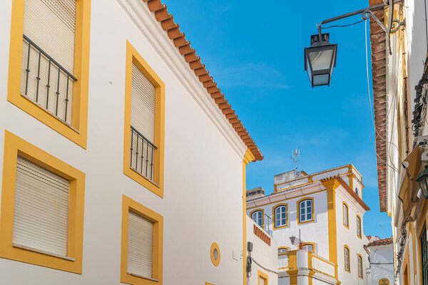 The view of narrow paved street of Evora with the cozy white and yellow houses. Evora. Alentejo. Portugal