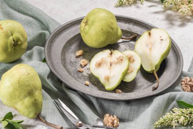 Fındık ile lezzetli armut. Çiçeklerle süslenmiş bir masa ve plakaya kesilmiş bir tabak armut