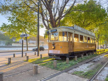 PORTO, PORTUGAL - 5 Nisan 2023: Porto caddesinde hareket eden ahşap tarihi klasik tramvay, şehrin sembolü. Massarelos 'ta gün batımında arka planda Arrabida köprüsü olan eski bir tramvay geçiyor. Portekiz