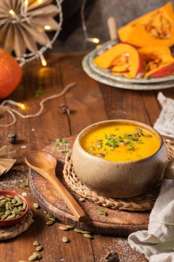 Lezzetli balkabağı kremalı çorba, organik bitkiler ve kabak tohumları eski seramik kasede. Sonbahar sıcacık akşam yemeği konsepti