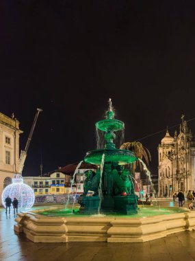 Porto, Portekiz - 9 Aralık 2023. Aslan çeşmesinin gece sahnesi. Yöre sakinleri ve ziyaretçiler Noel ışıklarını ve belediye binasının önündeki büyük Noel ağacını görmek için caddelerde yürüyorlar.