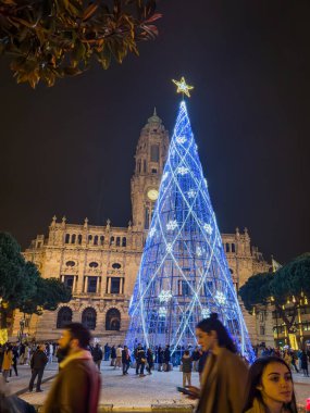 Porto, Portekiz - 9 Aralık 2023. Avenida dos Aliados ve Belediye Binası 'nın gece sahnesi Noel ağacıyla. Yöre sakinleri ve ziyaretçiler Noel ışıklarını ve belediye binasının önündeki büyük Noel ağacını görmek için caddelerde yürüyorlar.