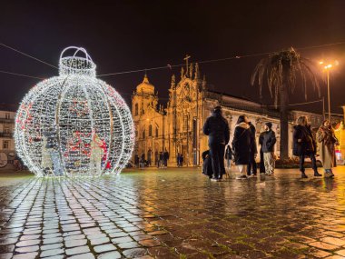 Porto, Portekiz - 9 Aralık 2023. Aslan çeşmesinin gece sahnesi. Yöre sakinleri ve ziyaretçiler Noel ışıklarını ve belediye binasının önündeki büyük Noel ağacını görmek için caddelerde yürüyorlar.