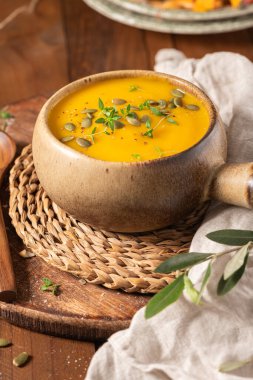 Lezzetli balkabağı kremalı çorba, organik bitkiler ve kabak tohumları eski seramik kasede. Sonbahar sıcacık akşam yemeği konsepti