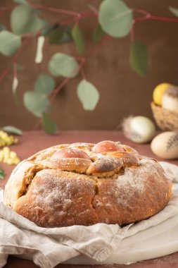 Yumurtalı geleneksel Portekiz Paskalya pastası. Tipik Folar de Vale de Ilhavo, Aveiro, Portekiz. Çiçekler ve renkli boyanmış yumurtalar Paskalya masasında tüylerle süslenmiş.