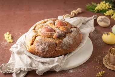 Yumurtalı geleneksel Portekiz Paskalya pastası. Tipik Folar de Vale de Ilhavo, Aveiro, Portekiz. Çiçekler ve renkli boyanmış yumurtalar Paskalya masasında tüylerle süslenmiş.