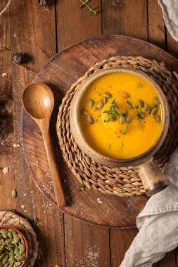 Lezzetli balkabağı kremalı çorba, organik bitkiler ve kabak tohumları eski seramik kasede. Sonbahar sıcacık akşam yemeği konsepti