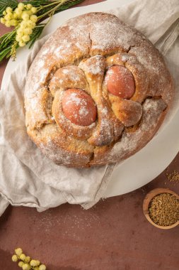 Yumurtalı geleneksel Portekiz Paskalya pastası. Tipik Folar de Vale de Ilhavo, Aveiro, Portekiz. Çiçekler ve renkli boyanmış yumurtalar Paskalya masasında tüylerle süslenmiş.