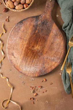 Mutfak masasının tahtasını Noel süsü, fındık ve Noel ziyafeti süslemeleri ile kesmek. Üst Manzara, kış tatili modelleme konsepti.