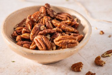 Bej arka planda bir kasede lezzetli cevizler, yakın plan.