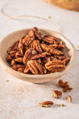 Bej arka planda bir kasede lezzetli cevizler, yakın plan.